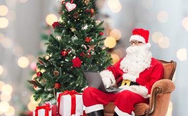 man in costume of santa claus with laptop