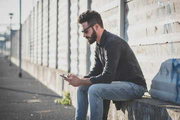 Obraz premium young handsome attractive bearded model man using smartphone