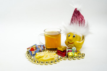Чай с лимоном и лимон в Рождественской шапочке, на белом фоне