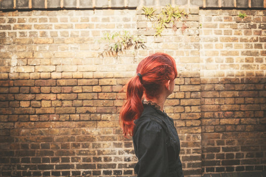 Young redhead woman walking in alley