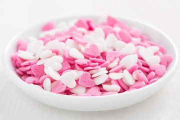 colored sugar hearts in a white bowl, close-up, selective focus