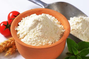 Wheat flour in terracotta dish and metal scoop