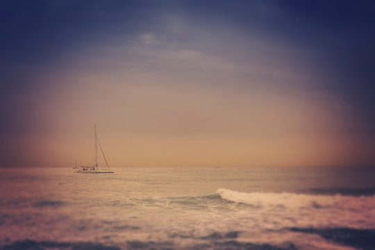 Fototapeta blurred retro image of small yacht in the sea, with tilt shift e