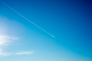 airplane flies in white clouds in a blue sky and leaving trail