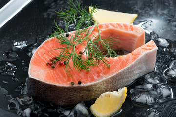 raw salmon steak with dill and lemon on ice