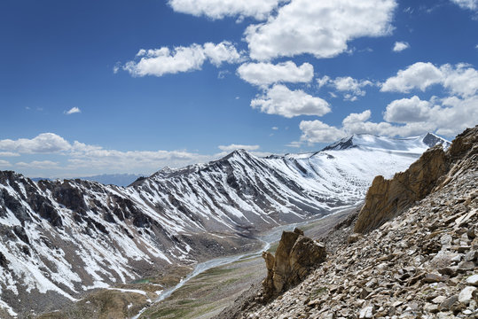 Sharp snow covered mountain ridge with river and green valley
