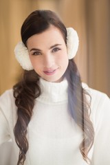 Pretty brunette with ear muffs smiling at camera