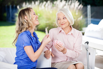 Cheerful Granddaughter Showing Playing Cards To Grandmother