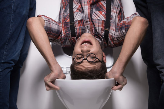 man is standing upside down on toilet bowl.