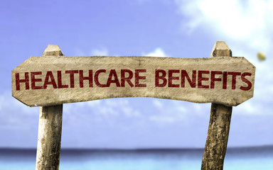 Healthcare Benefits wooden sign with a beach on background