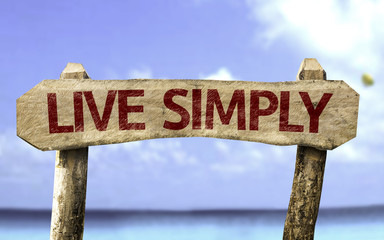 Live Simply wooden sign with a beach on background