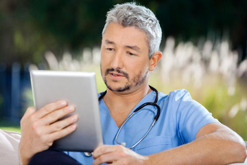 Obraz premium Male Caretaker Using Tablet PC While Sitting