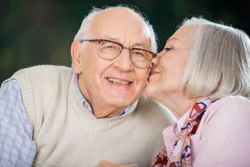 Senior Woman Kissing On Man's Cheek
