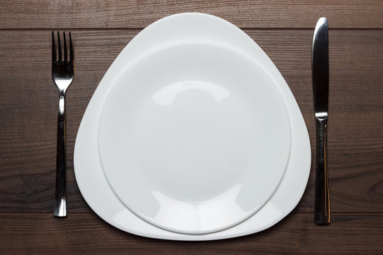 white plates with knife and fork on wooden table
