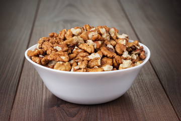 walnuts in the white bowl on wooden table