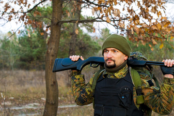 Fototapeta premium Soldier with a rifle in the autumn forest