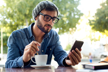 Modern young man with mobile phone in the street.