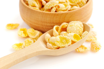 Cornflakes in a wooden spoon on white background