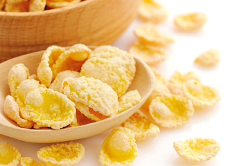 Cornflakes in a wooden spoon on white background