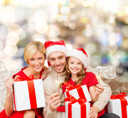 Obraz na płótnie Canvas happy family in santa helper hats with gift boxes