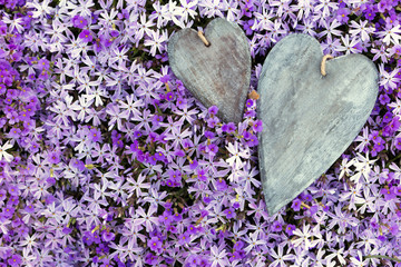 Grußkarte aus vielen lila Blüten und zwei Herzen aus Holz