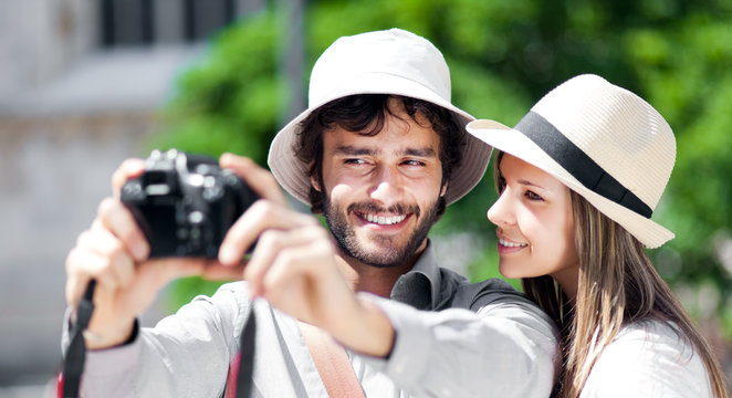 Smiling tourist showing photos to his girlfriend