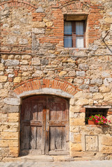 Fototapeta na wymiar Old walls and doors decorated with flowers in Monteriggioni, Tus