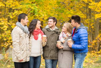 group of smiling friend with coffee cups in park