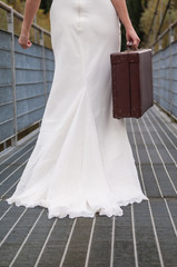 bride walking on the bridge with her suitcase