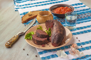 Black pudding sausages on a plate with glass of vodka