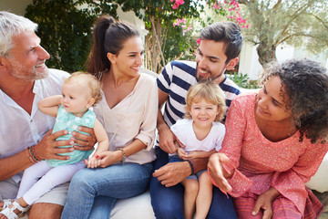 Multi Generation Family Sitting Outdoors At Home Together