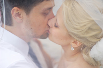 Bride and groom kissing under the veil