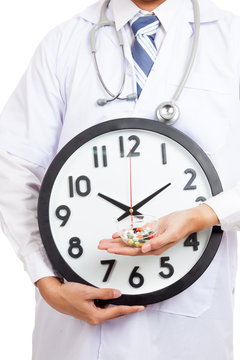 Asian male doctor show a clock and pills