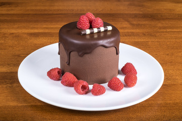 Rich Chocolate Cake Decorated with Raspberries On White Plate