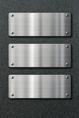 three stainless steel metal plates on black background