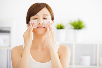 Beautiful  young woman cleaning her face with cotton