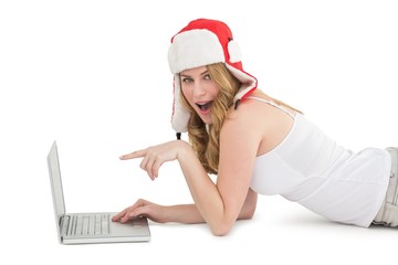 Woman lying on the floor while pointing to laptop