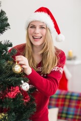 Smiling woman hanging christmas decorations on tree