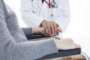 Doctor holding the hand of a wheelchair patient