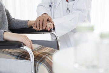 Doctor holding the hand of a wheelchair patient