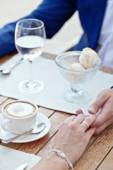 woman's and man's hands holding in cafe with ice-cream and coffe