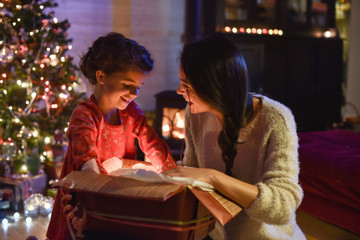 Lovely mother and her daugther opening a gift in front of the Ch