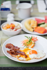 Hotel breakfast. Fried eggs with bacon and fruit