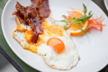 Hotel breakfast. Fried eggs with bacon and fruit