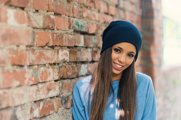 Smiling teenager portrait outdoors against brick wall.