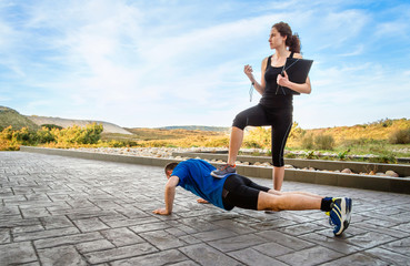 Girl coach training hard a man through push ups