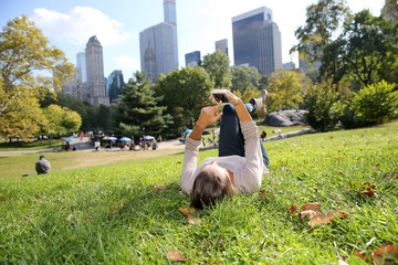 Young woman in Central Park using smartphone - obrazy, fototapety, plakaty