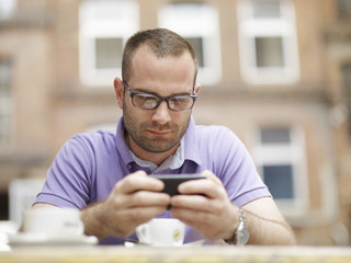 Portrait of a happy young man sitting outdoors with mobile phone