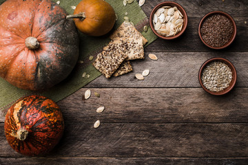 Rustic style pumpkins with seeds and cookies on wooden table