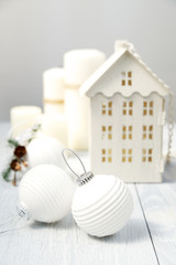 Christmas house and balls on a white wooden background